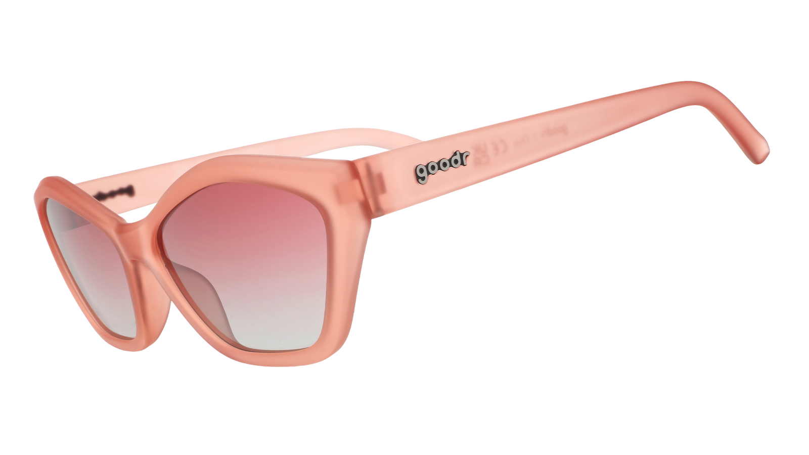Three-quarter angle view of geometric sunglasses with translucent coral pink frames and gradient lenses against a white background.