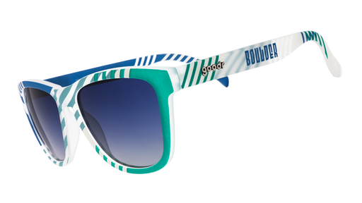 Three-quarter angle view of blue and green sunglasses with an asymmetrical striped print, Boulder logo, and blue gradient lenses.