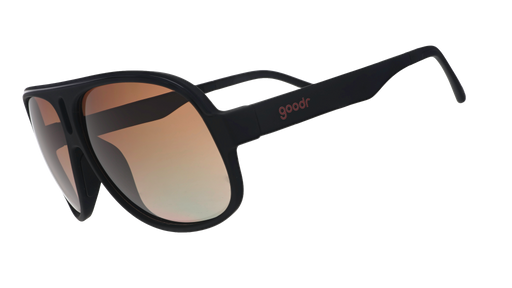 Three-quarter angle view of black aviator sunglasses with amber gradient lenses against a white background.