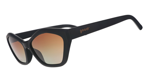 Three-quarter angle view of black geometric cat-eye sunglasses with amber gradient lenses against a white background.