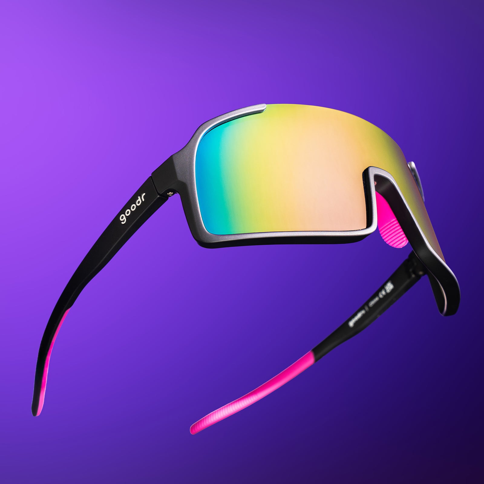 Black wrap sunglasses with purple reflective lenses, hot pink nose and temple grips floating against a purple backdrop.