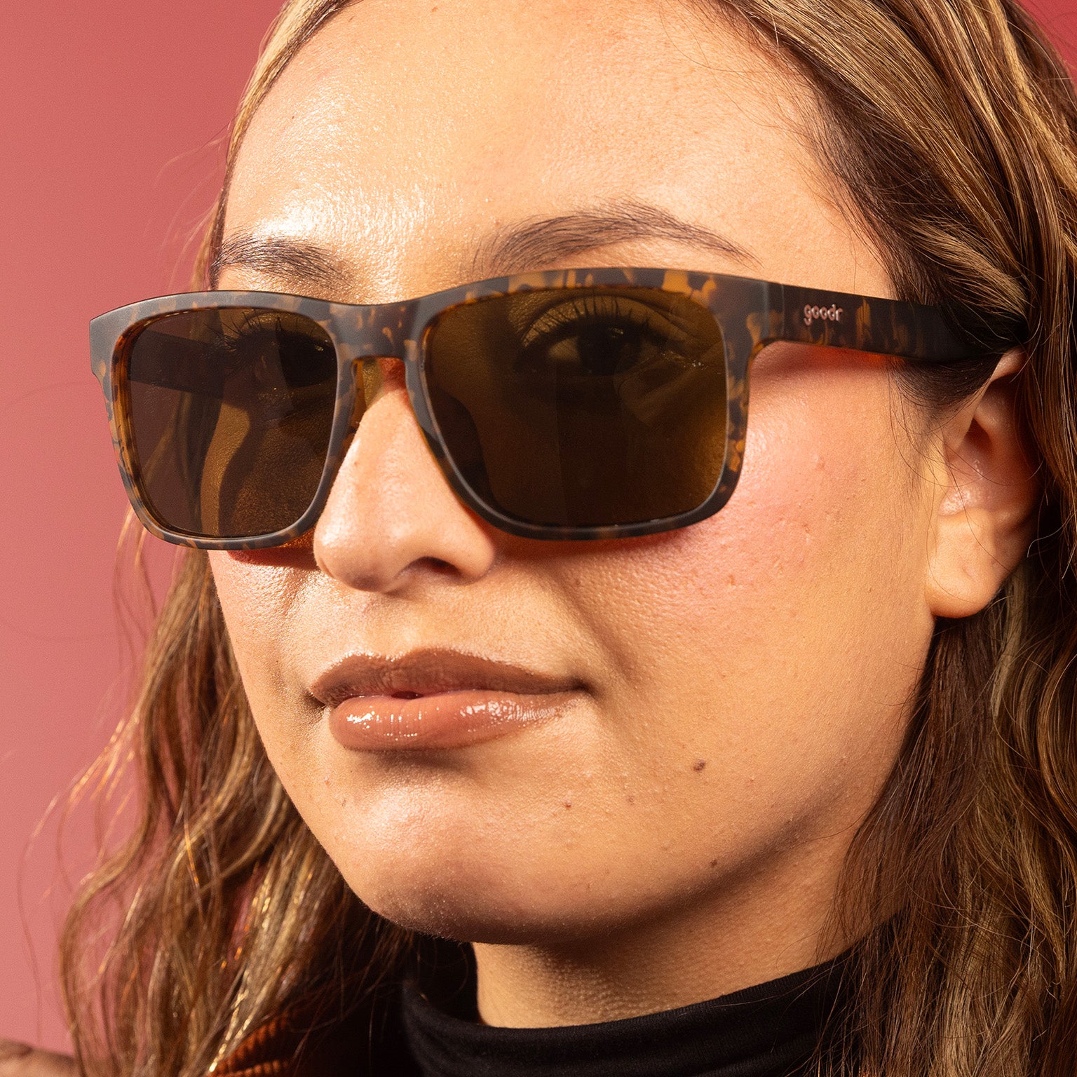 A stylish woman with wavy blonde hair looks at the camera brown tortoiseshell Grand Gs with brown non-reflective lenses.