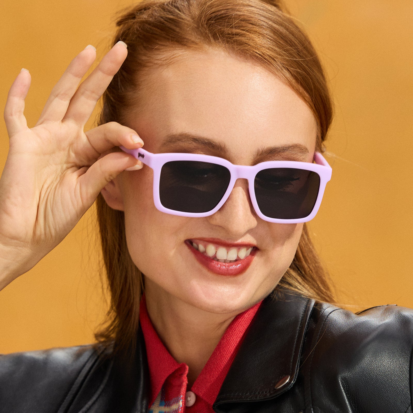 A woman with long red hair poses confidently in a pair of lavender square Slate G sunglasses.