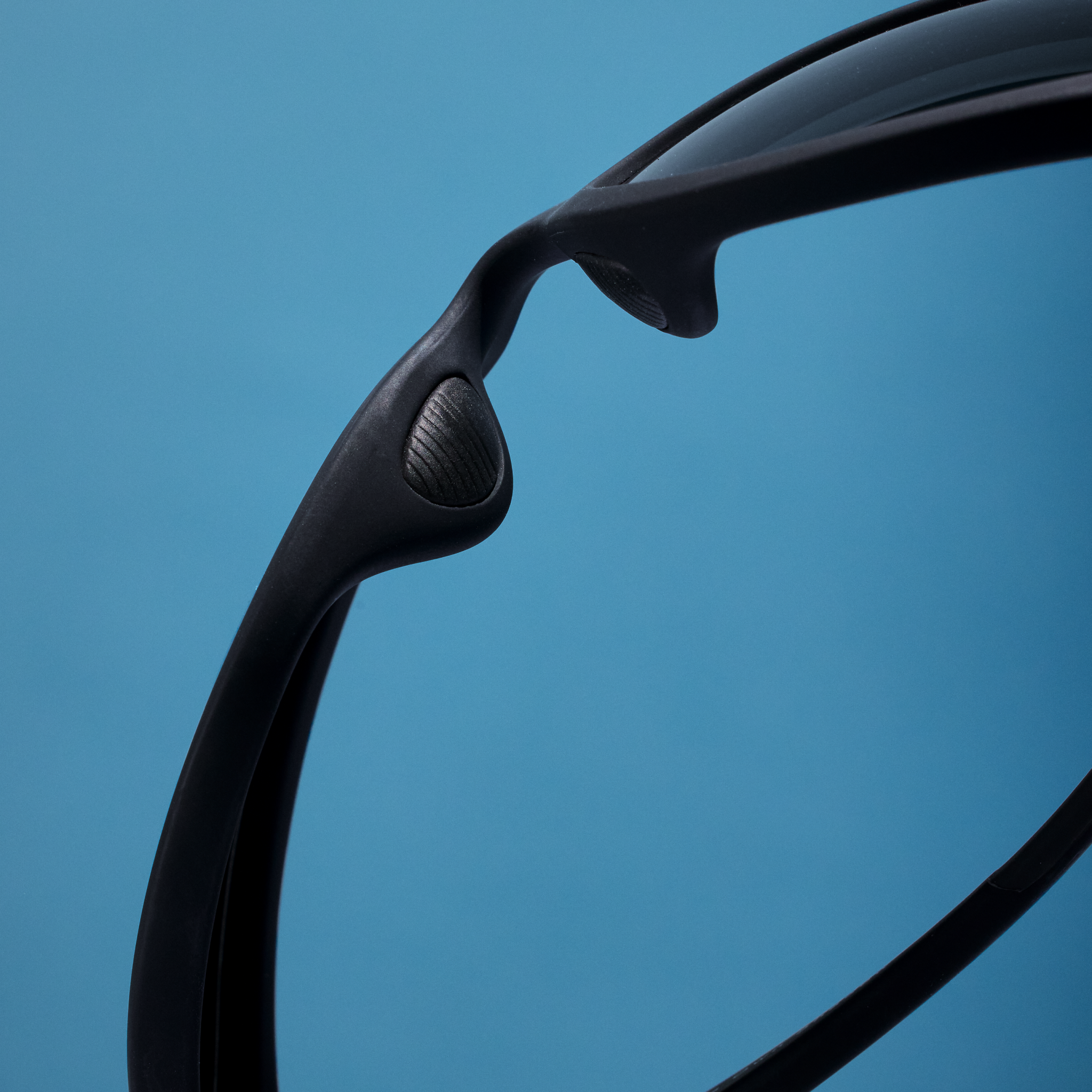 Close-up of the nose pad on black wraparound sunglasses with black non-reflective lenses.