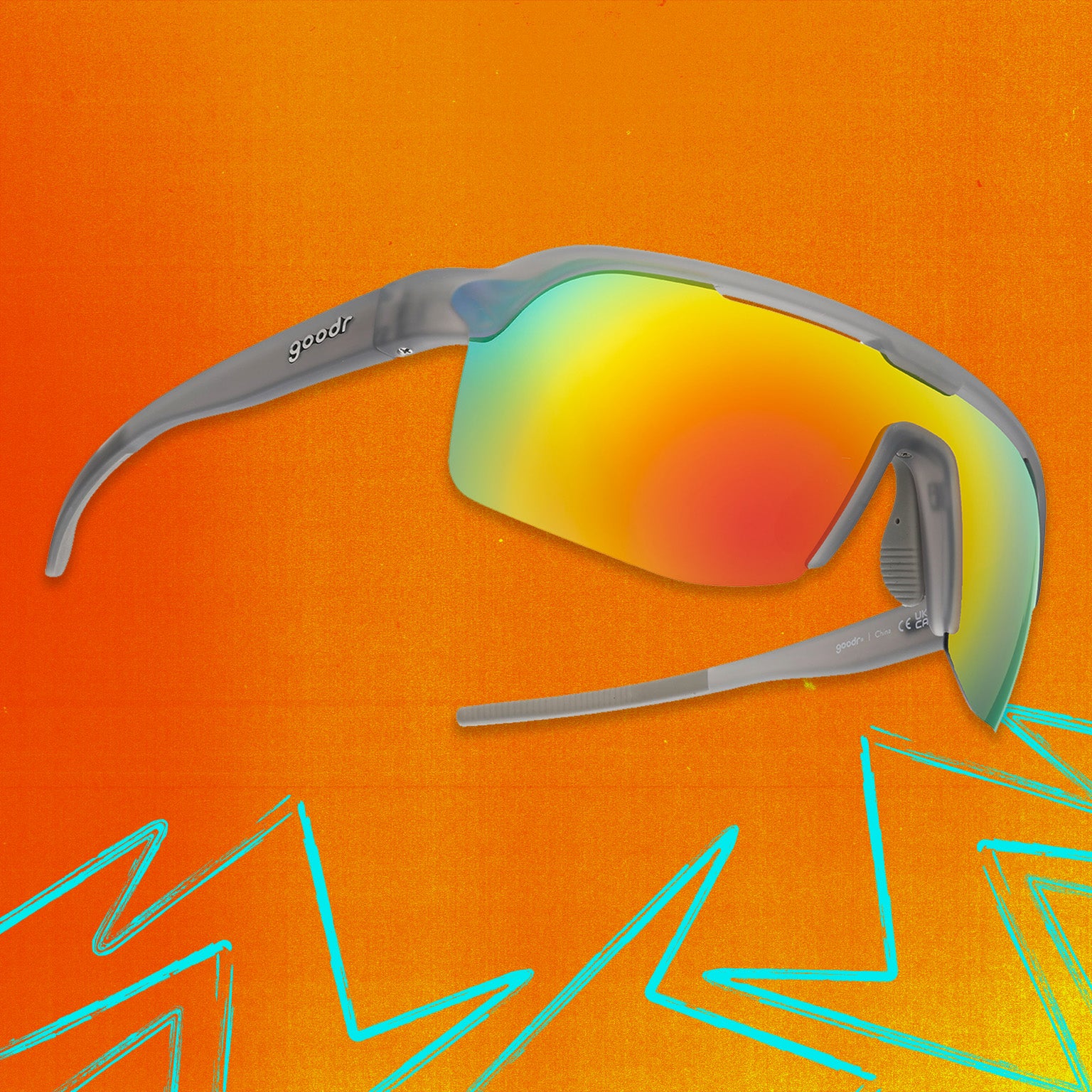 Three-quarter angle view of gray shield sunglasses with orange reflective wrap lenses tilted up on an orange background.