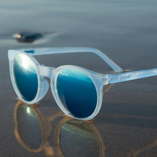 Three-quarter view of translucent blue-gray Circle Gs with ice blue reflective lenses sitting at the wet shoreline.
