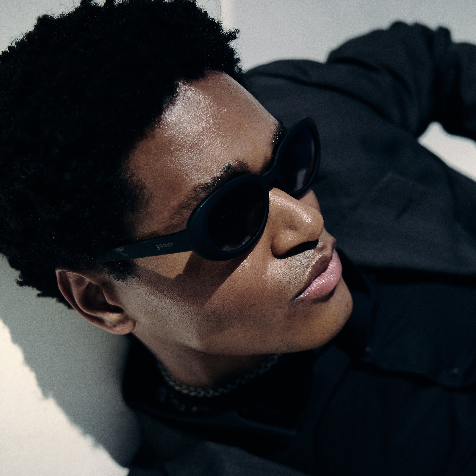 Side profile view of a man wearing black oval sunglasses with polarized lenses.