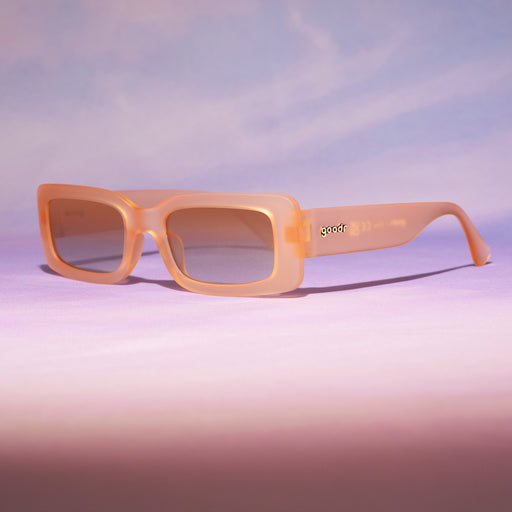 Three-quarter view of translucent peach rectangular Luxe Gs sitting on a purplish-pink backdrop reminiscent of a sunset.
