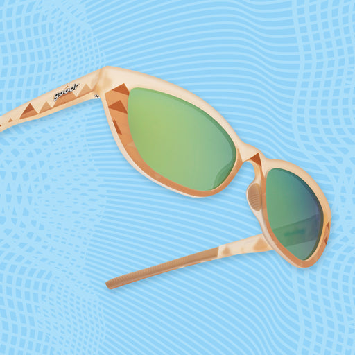 Light brown sunglasses with green mirrored lenses and pyramid-inspired geometric patterns on blue.