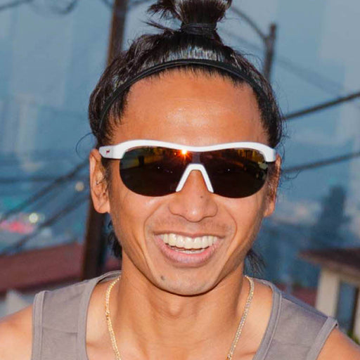 High-angle view of a model wearing white wrap shield sunglasses with red accents and fire-red reflective lenses.