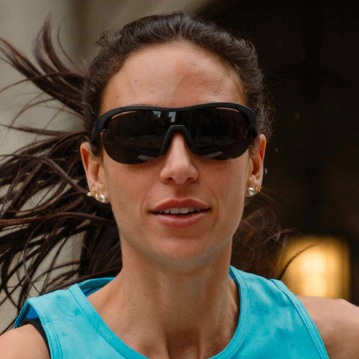 Model running while wearing black wraparound shield sunglasses with black polarized lenses.