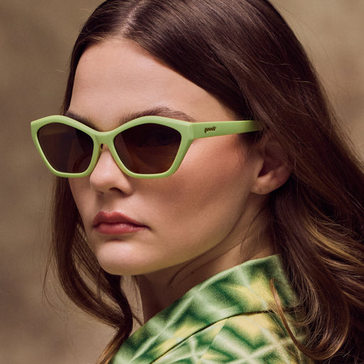Woman wearing green sunglasses with a blurred background