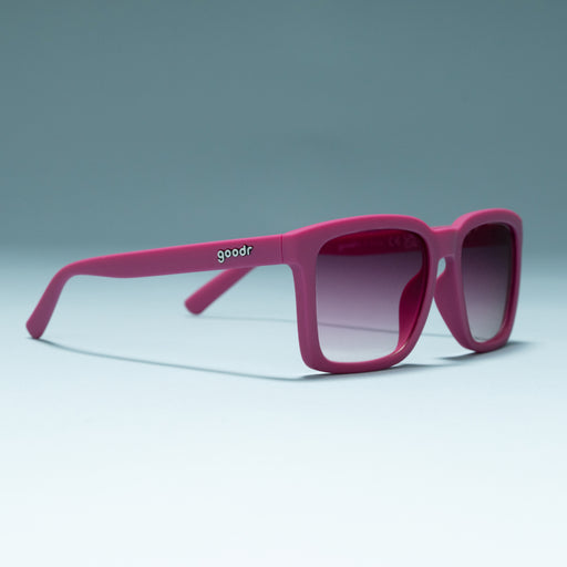 Three-quarter angle view of purple shades w/ purple gradient lenses+ a classic square silhouette on a flat surface.