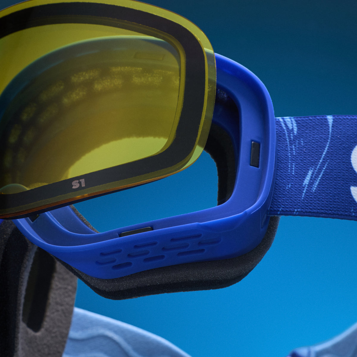 Close-up of yellow low-light lens being swapped onto blue snow goggles with a magnetic lens system.