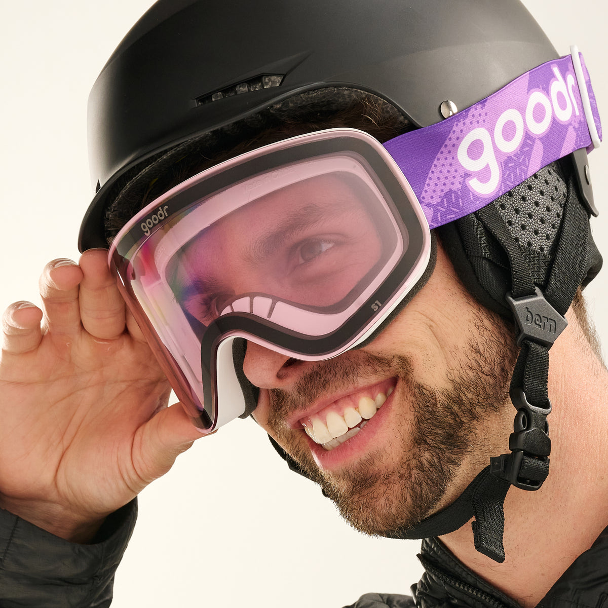 Smiling skier wearing pale pink goodr goggles and adjusting the frame.