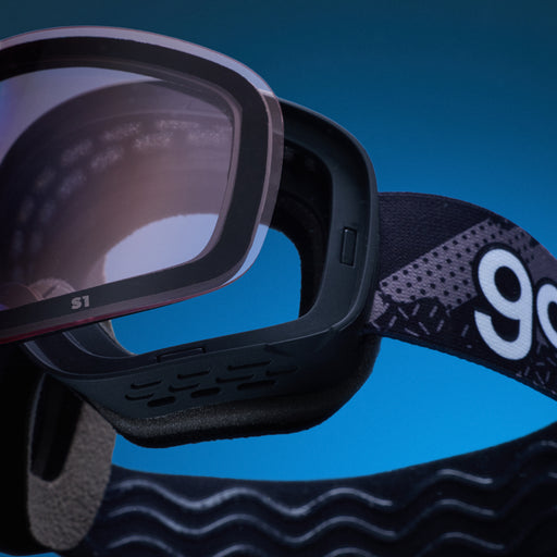 Pale pink replacement lens resting above black goodr ski goggles.