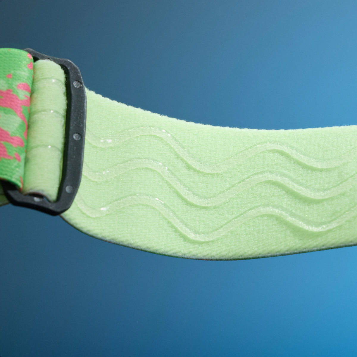 Close-up of pale green elastic goggle strap with raised wavy silicone grip lines.