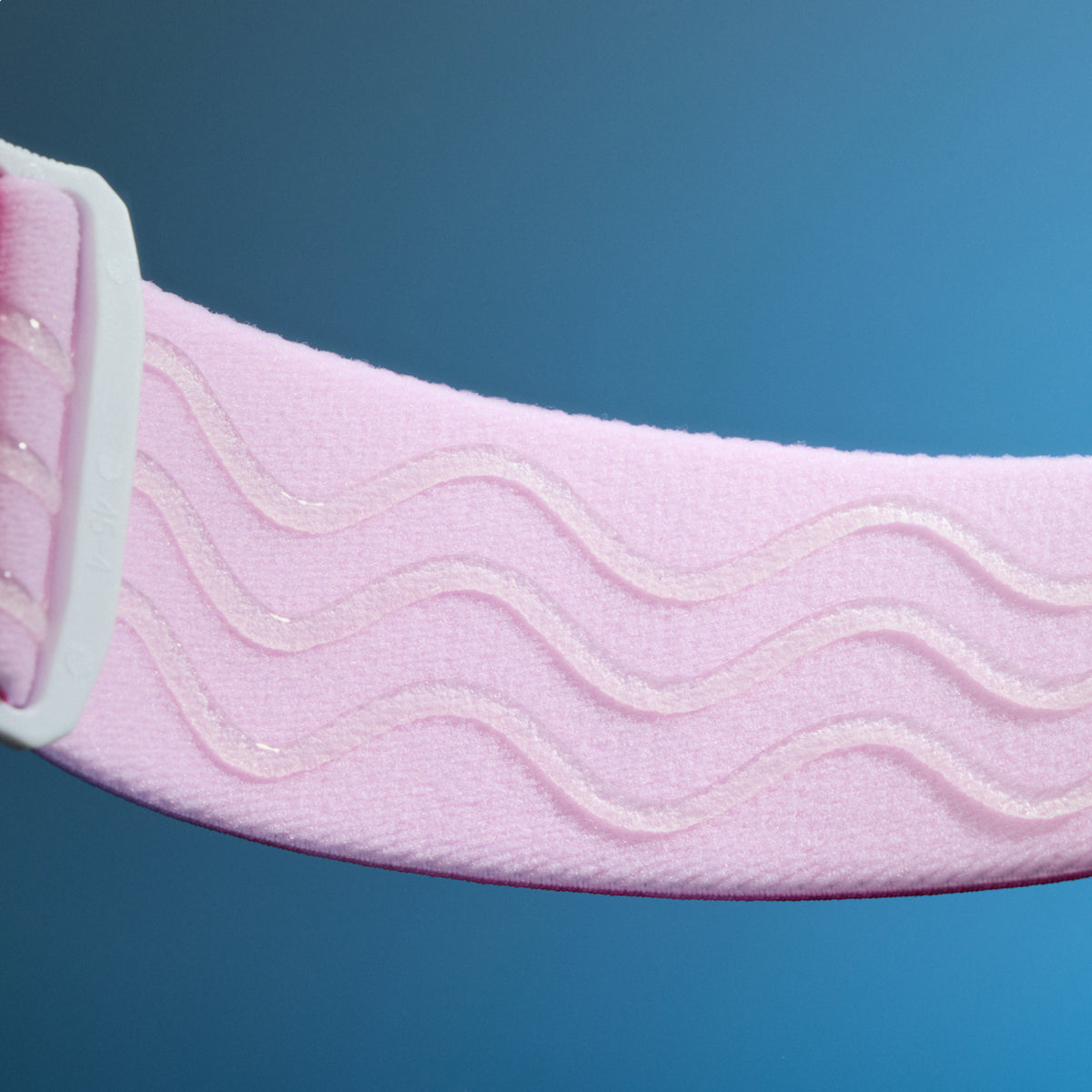  Close-up of pale pink elastic goggle strap with raised wavy silicone grip lines.