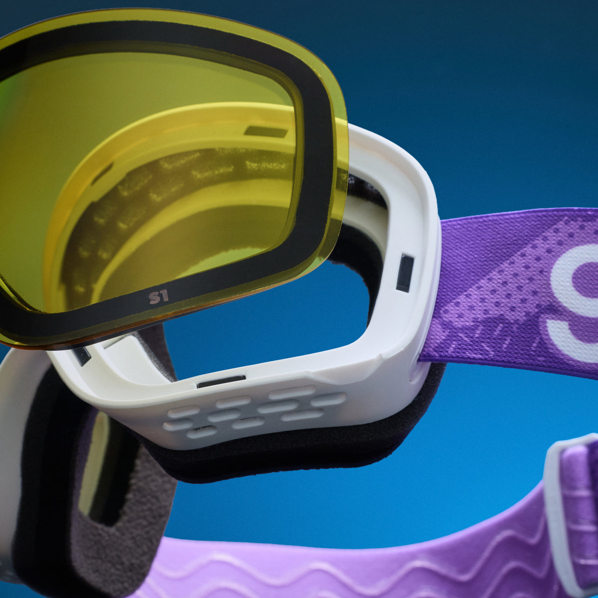 Close-up of yellow low-light lens being swapped onto white snow goggles with a magnetic lens system.