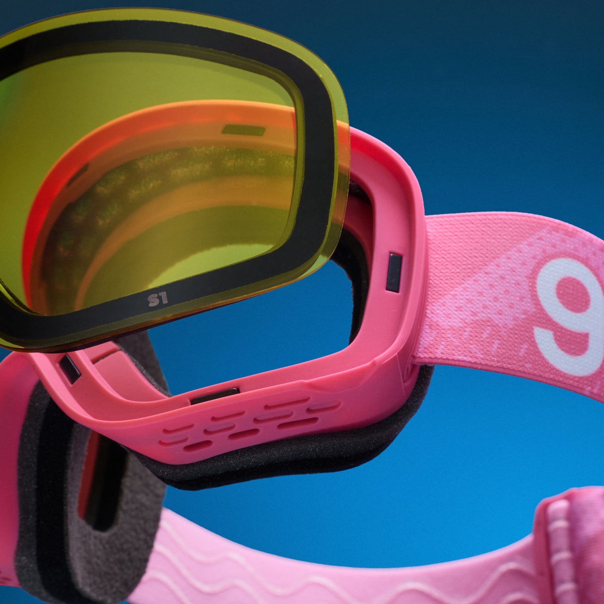 Close-up of yellow low-light lens being swapped onto pink snow goggles with a magnetic lens system.
