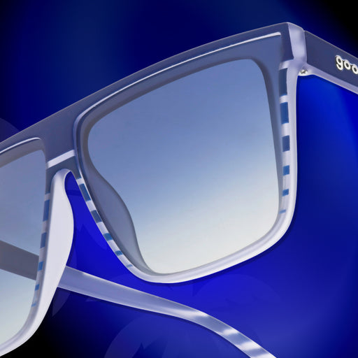 Close-up of the temple of a pair of retro-striped, translucent blue-purple Fly G sunglasses against a vivid blue background.